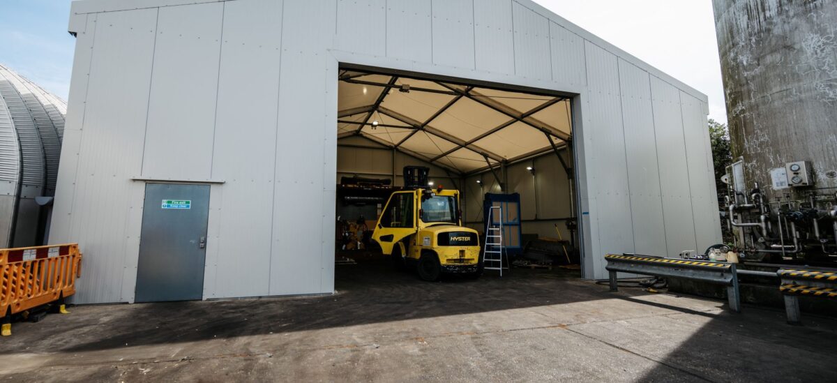 large temporary building with an open rolling shutter door with a forklift parked inside