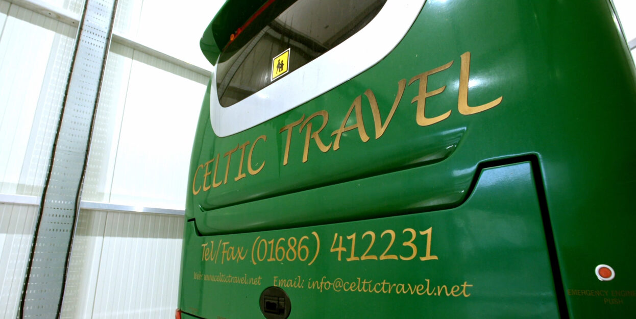 view of a back of a green bus with a celtic travel logo