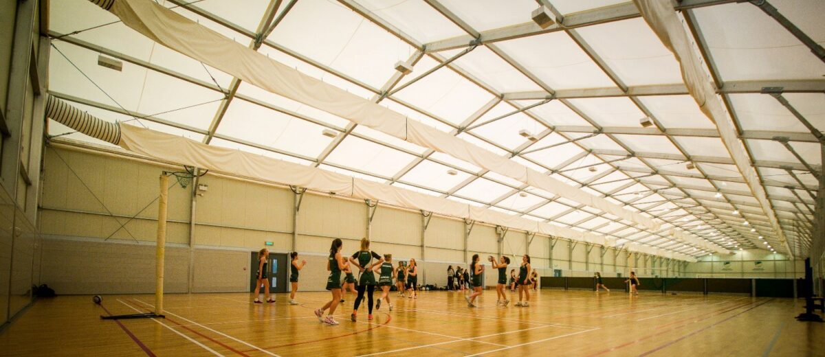 bespoke structure designed with a sports hall within and people playing netball