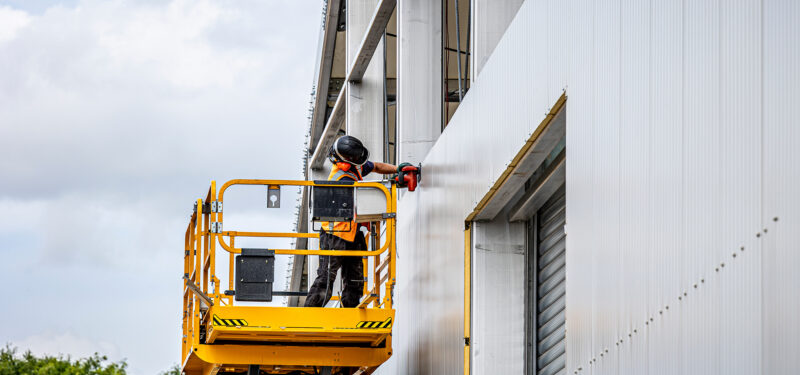 mid build of a bespoke structure with a worker on cherry picker screwing in and building